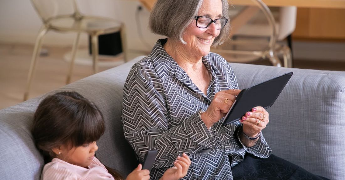 E-Reader - Girl and Smiling Woman with E-Reader Sitting on Sofa